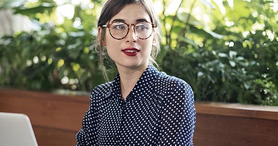 Young woman with glasses wearing polka dot shirt