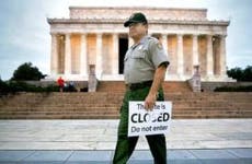 Government employee holding 'This site is CLOSED' sign | Andrew Harrer/Bloomberg/Getty Images