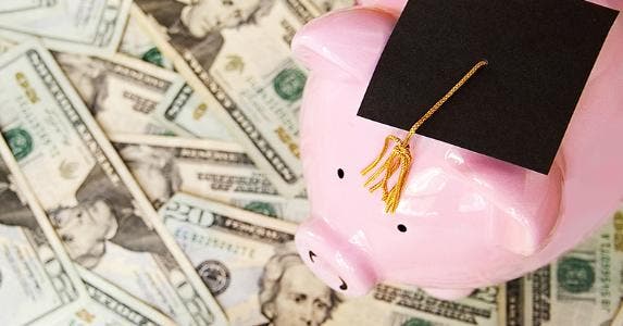 Piggy bank wearing graduation cap on top of $20 bills © zimmytws/Shutterstock.com
