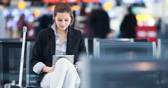 6 best airports in the US for a long layover Young woman browsing tablet computer while waiting for her next flight © l i g h t p o e t/Shutterstock.com