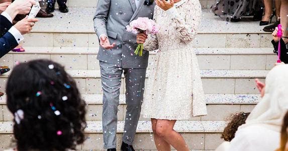 How much does a wedding cost? Throwing confetti at newlyweds walking down the stairs | Sweet Ice Cream Photography/Unsplash