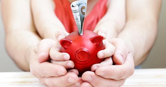 Father and child holding red piggy bank © iStock