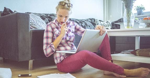 Young woman with laptop on hardwood floor © iStock