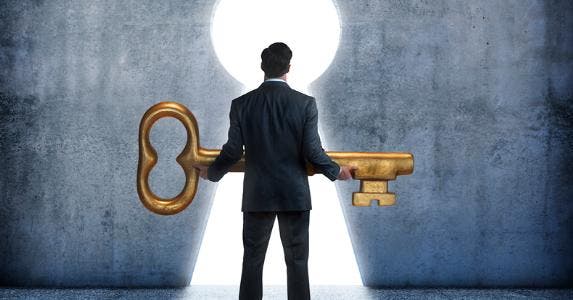 Man holding large key at keyhole doorway © iStock