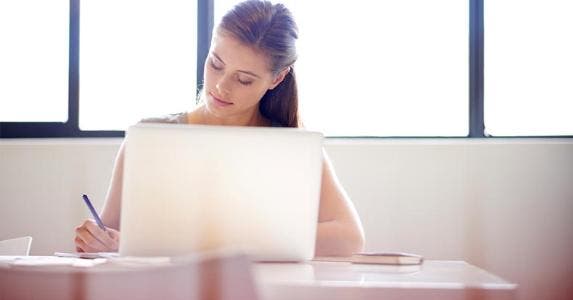 Top 3 credit-building tips for millennials Millennial working at her desk © iStock