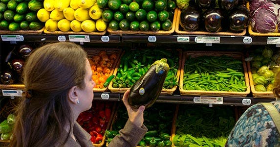 Woman looking at an eggplant at the grocery store