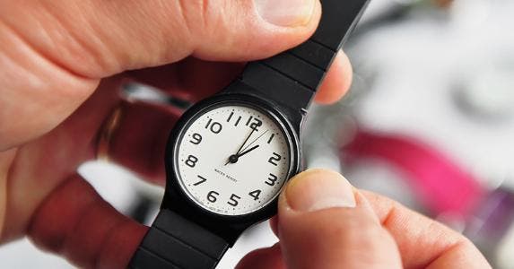 Man turning dial on wristwatch © ChameleonsEye/Shutterstock.com