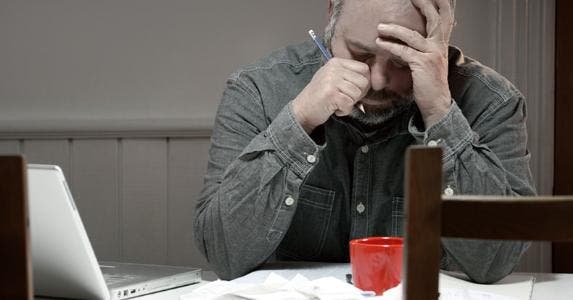 Answers to 10 tough bankruptcy questions Stressed man in dining room overwhelmed with debt | iStock.com/Fertnig