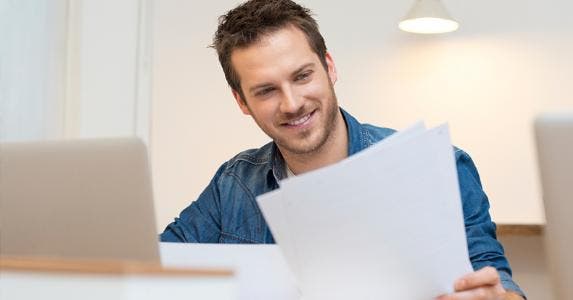 Man smiling over his papers | iStock.com