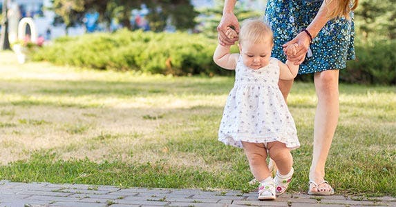 Mom helping baby daughter walk