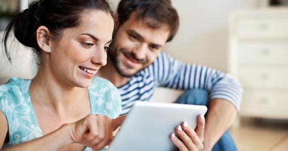 Young couple sitting on floor browing on tablet © iStock