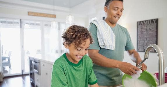 Survey: Mortgages strain parents' ability to save Dad and son doing dishes in kitchen | Hero Images/Getty Images