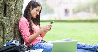 Student sitting against tree on phone © arek_malang/Shutterstock.com