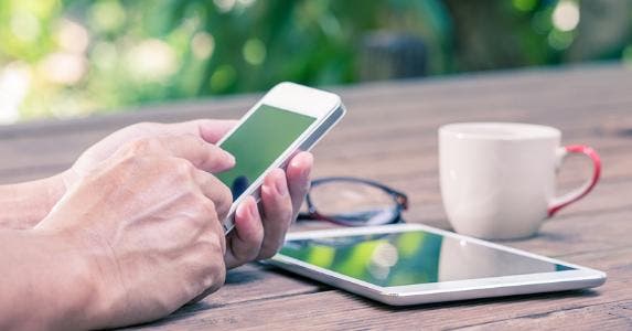 Using mobile and tablet outside at table © LittleStocker/Shutterstock.com
