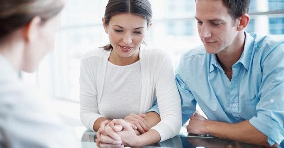 Young couple looking at paperwork, holding hands © iStock