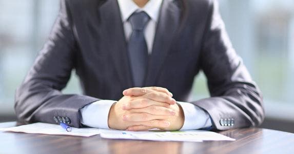 Businessman with hands folded on desk © YURALAITS ALBERT/Shutterstock.com