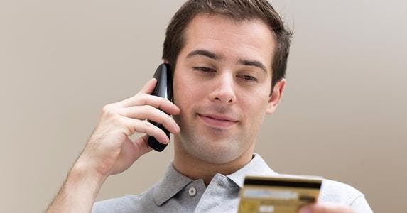 Man talking on cellphone while holding credit card © LDprod/Shutterstock.com