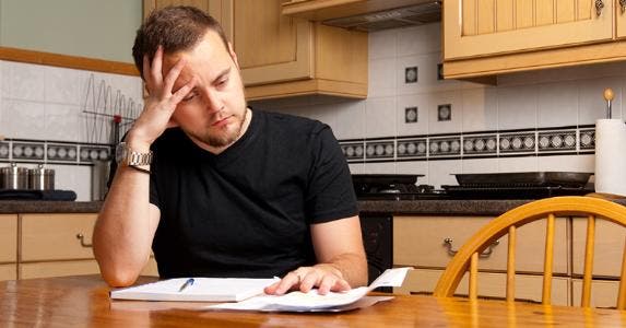 Man looking at debt at table © iStock