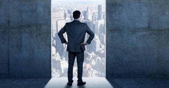 Businessman standing in open doorway to city © iStock