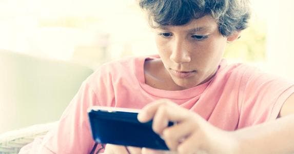 3 apps that can teach kids financial responsibility Teenage boy playing smartphone | iStock.com/Guillermo Perales Gonzale