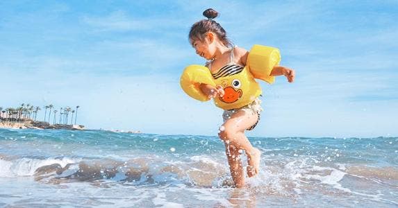 Young girl playing in the ocean water | Leo Rivas-Micoud/Snapstock