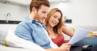 Couple looking over document on couch © Monkey Business Images/Shutterstock.com