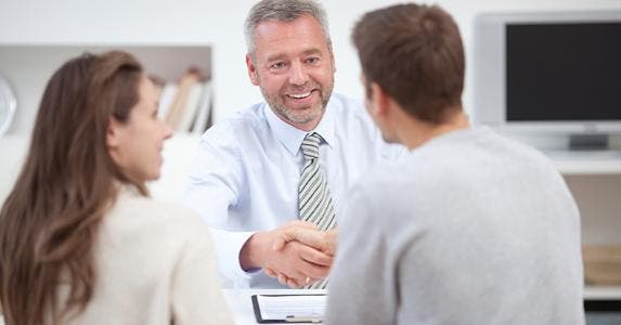 Male adviser shaking hands with client couple © iStock