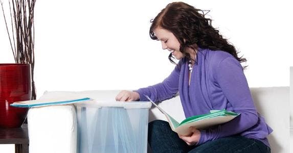3 tips to snag a personal loan for sudden costs Woman sorting files on the couch in living room | iStock.com/LivingImages