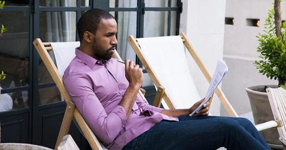 Why you shouldn't pry into your spouse's credit Man in purple shirt reading paperwork in patio chair | PhotoAlto/Sigrid Olsson/Getty Imagesm