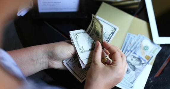Tipping etiquette in the US and abroad Counting out money © iStock