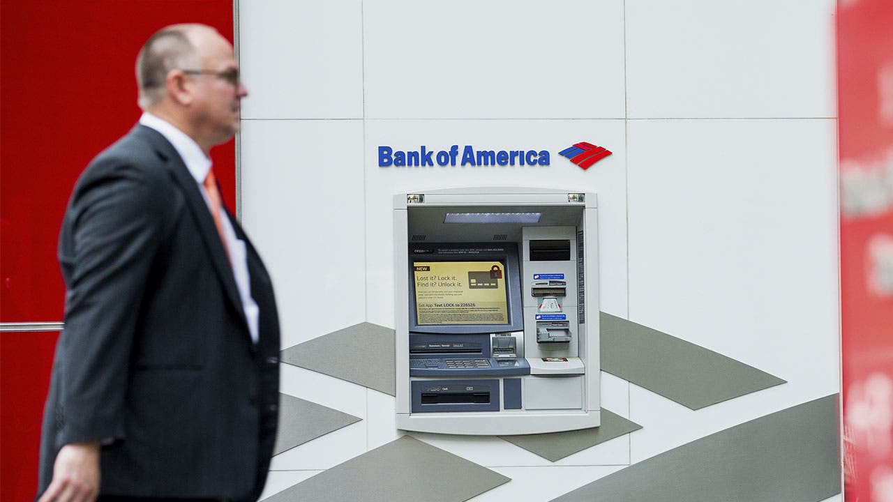 Man in suit walking past Bank of America ATM