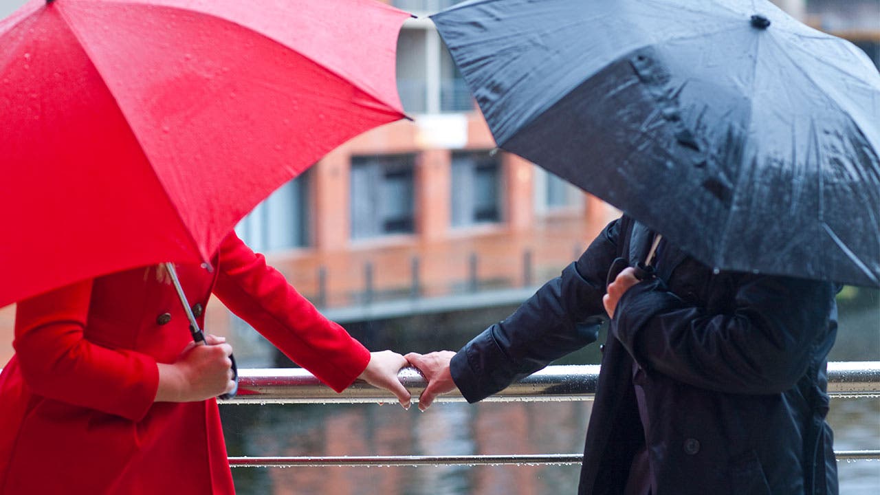Man and woman with umbrellas touch