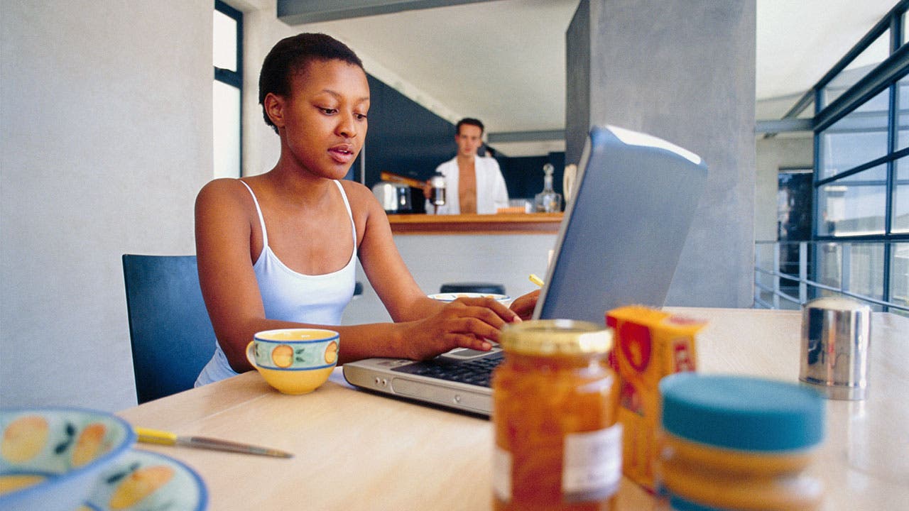 Woman using laptop at kitchen table