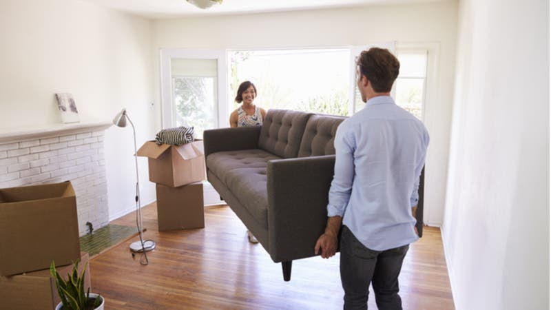 Couple carrying new couch into living room