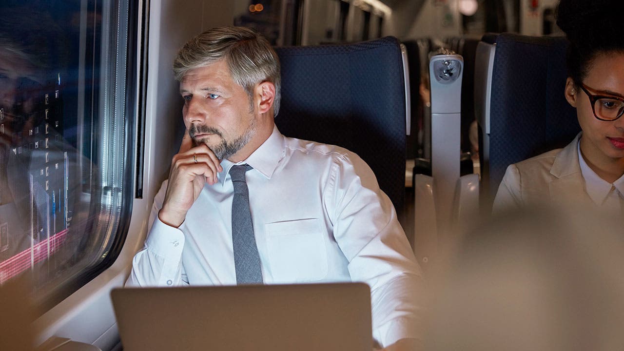 Man looks out train window with laptop