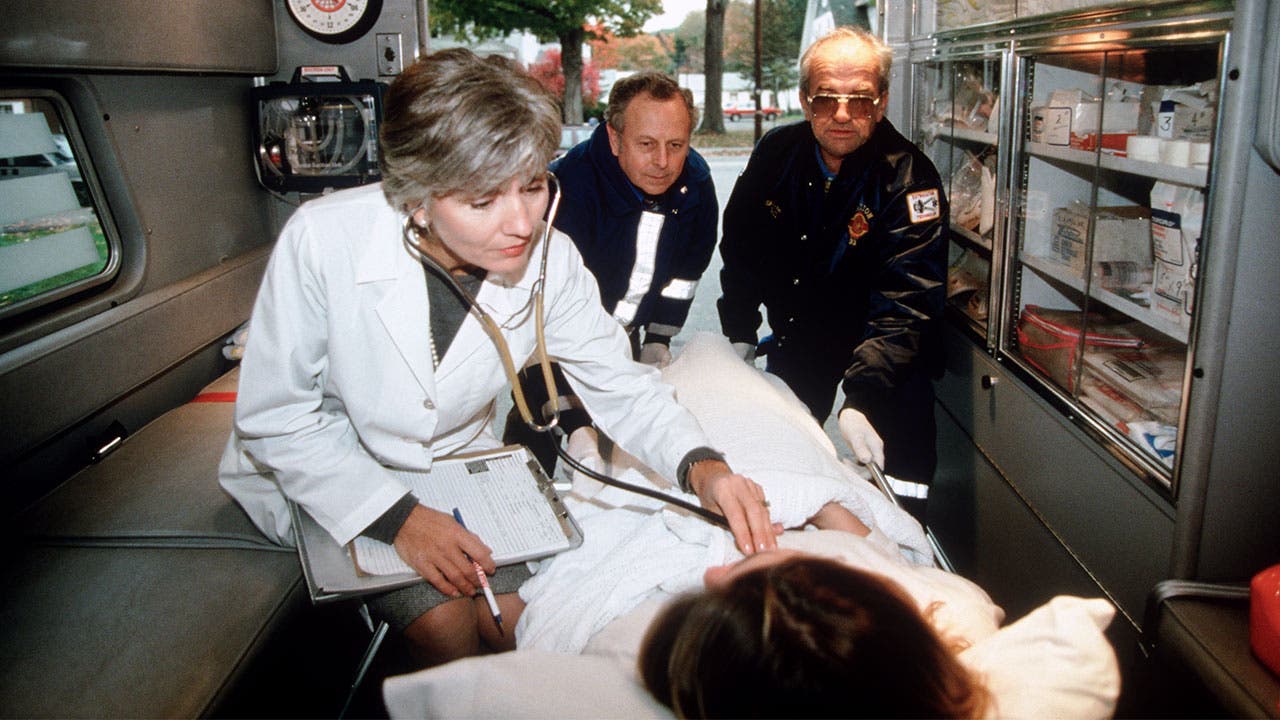 Doctor listening for heartbeat in ambulance