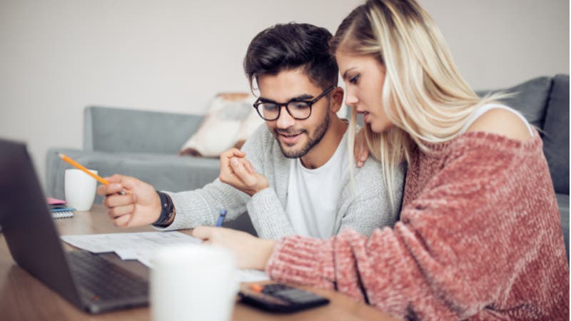 Young couple analyzing paperwork and computer