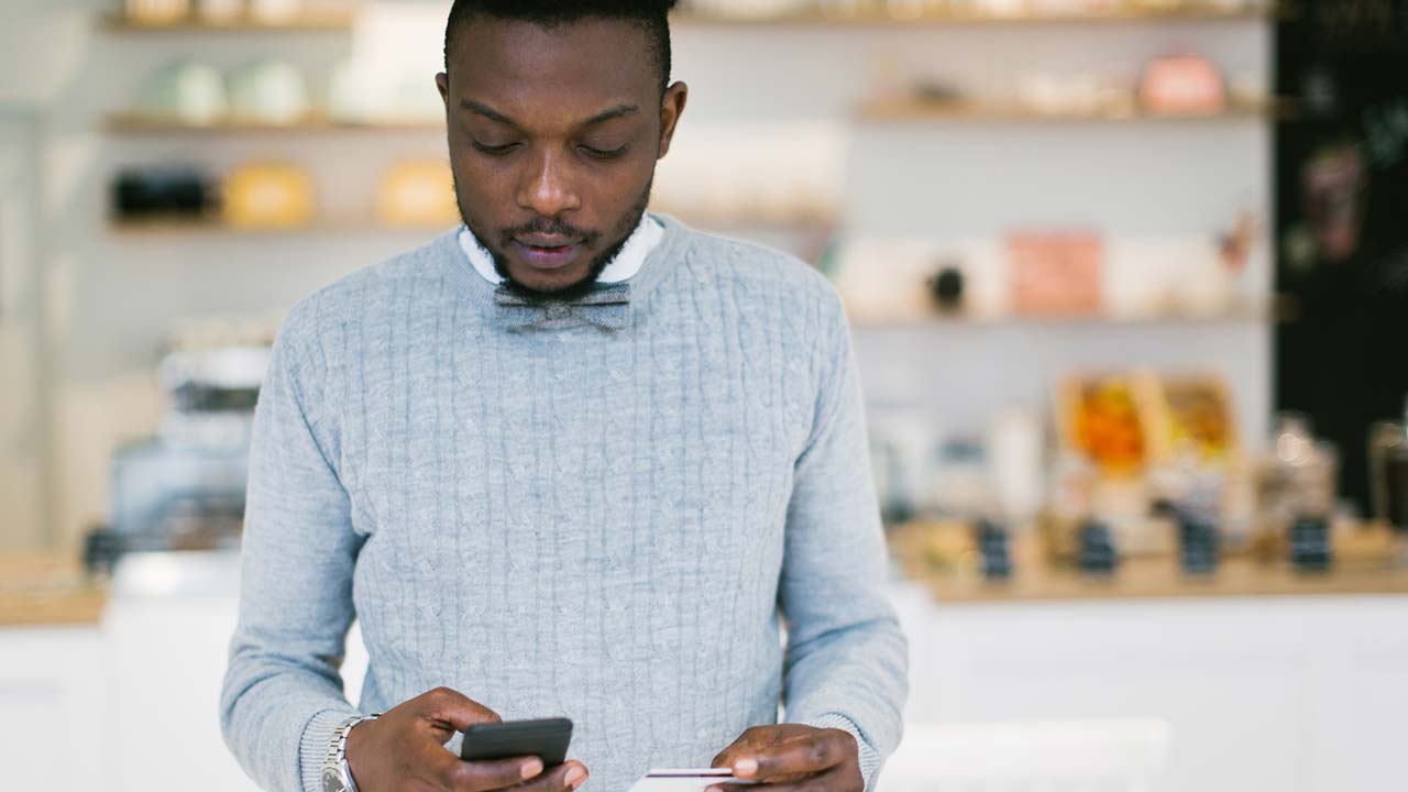 Young man holding debit card and mobile phone