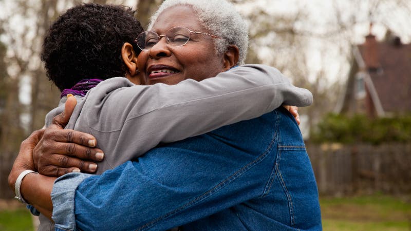senior African mother hugging daughter
