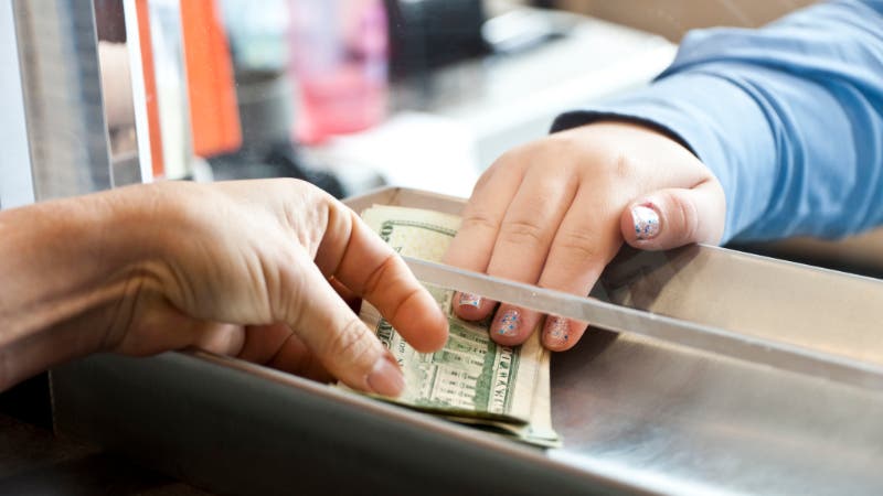 woman handing over cash in bank