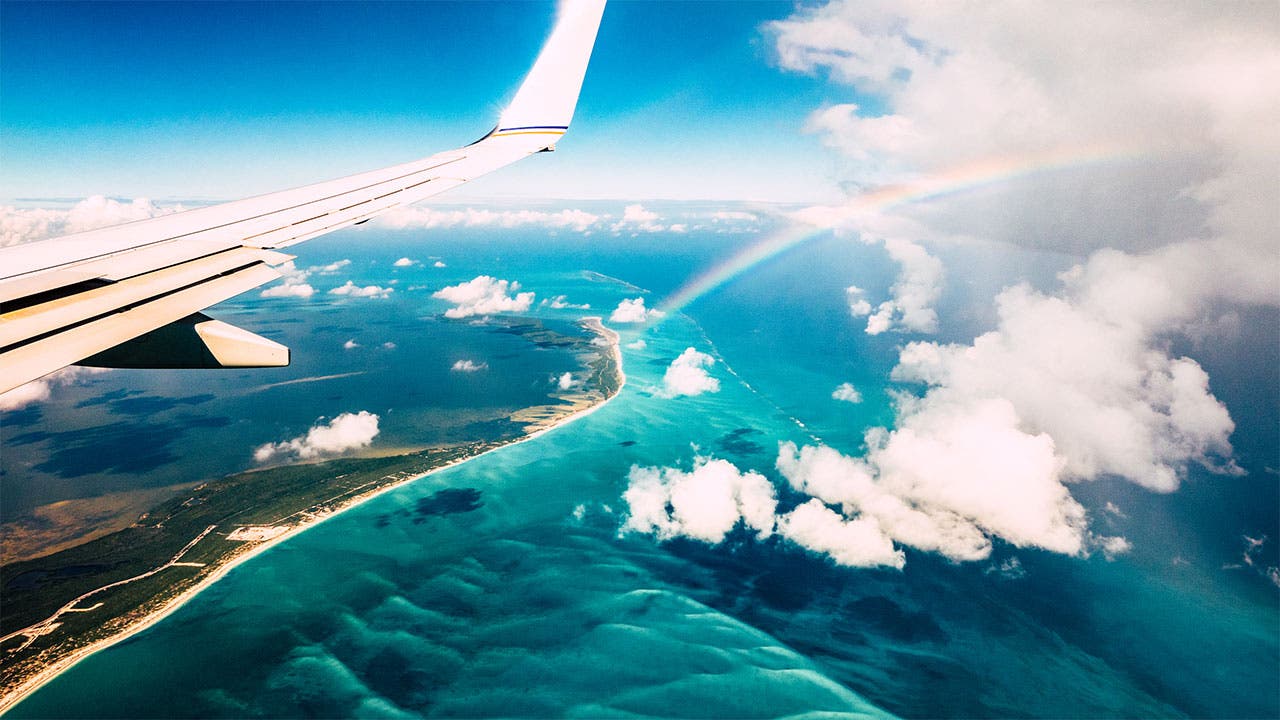 Plane over an island with a rainbow