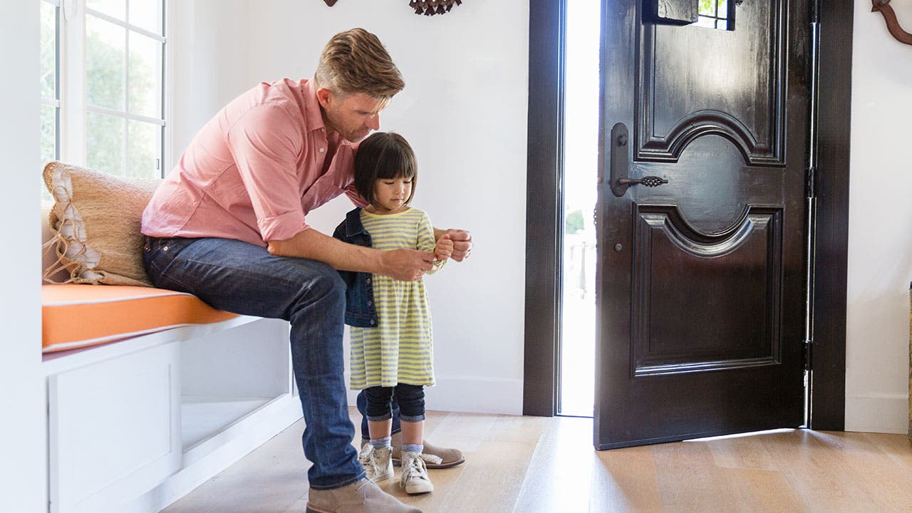 Father helps put coat on daughter