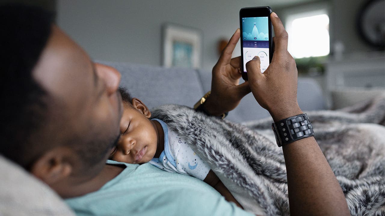 Father looking at phone while his son sleeps