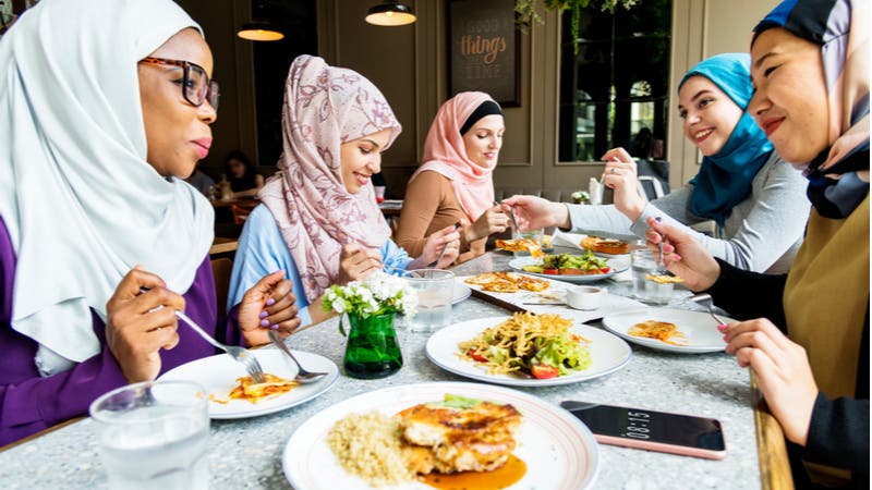 Group of young muslim women enjoying a meal at a restaurant