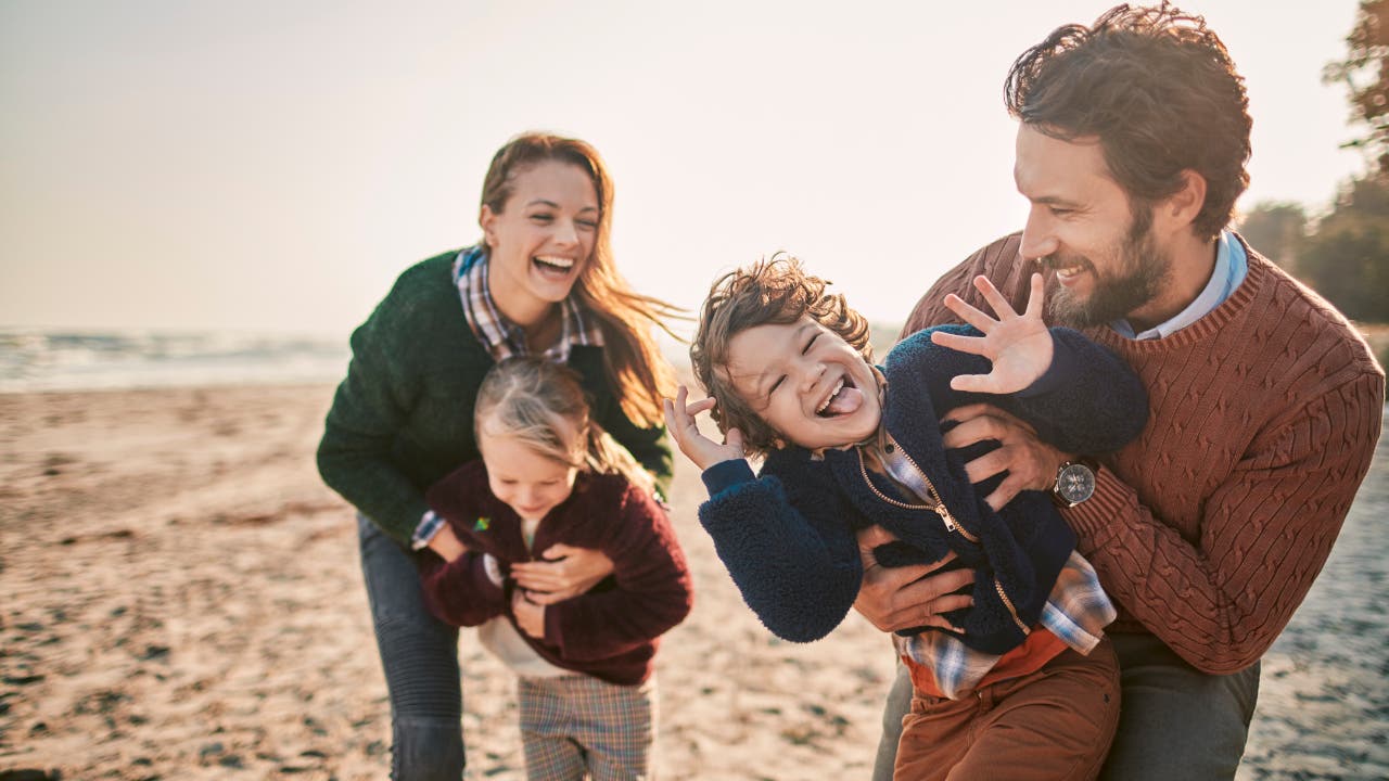 young family laughing at the beach