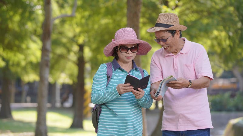 An older Asian couple are looking at travel books