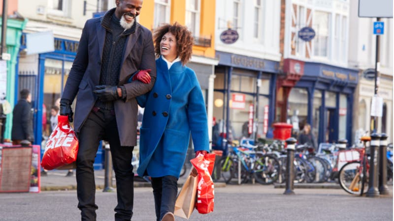 Middle-aged couple strolling arm-in-arm with shopping bags