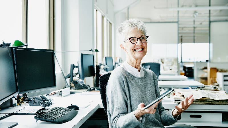 An older businesswoman sits smiling in an office