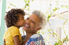 A young Black girls kisses her older Black relative